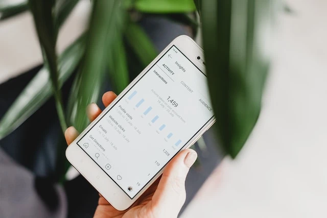 A hand holding a phone open to Instagram analytics