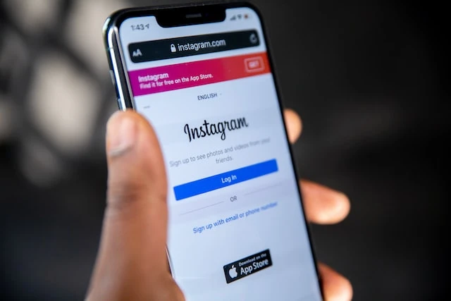 A hand holding a phone open to the Instagram login page