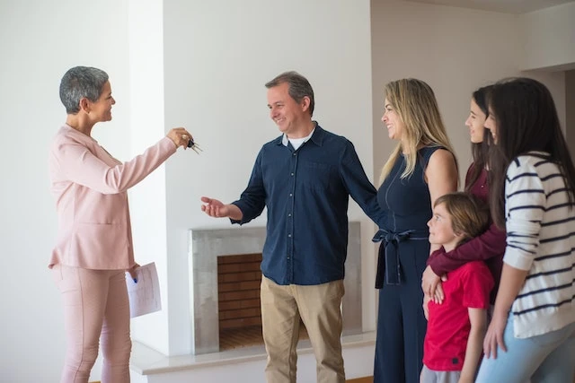a smiling family of five people receiving keys from a happy landlord