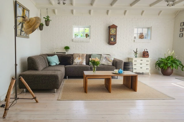 A white living room with an L-shaped grey couch and wooden nesting tables