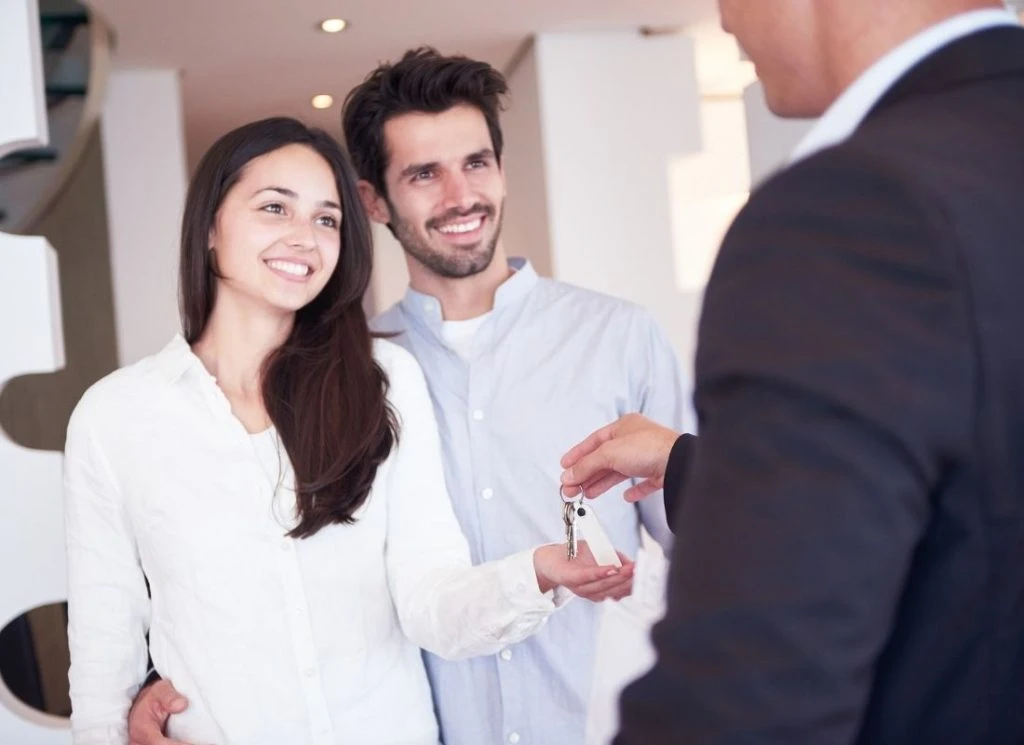 A young couple receiving keys from their property manager