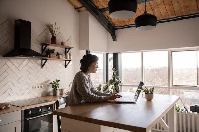 A young person in a kitchen using their laptop to report rent payments