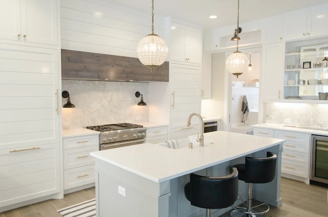 Interior of a modern white kitchen with a large island and chrome appliances