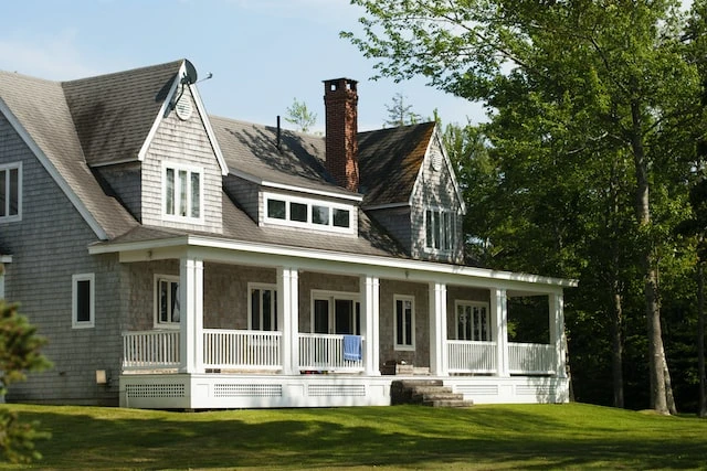 Exterior of a large grey house with a white porch and green lawn