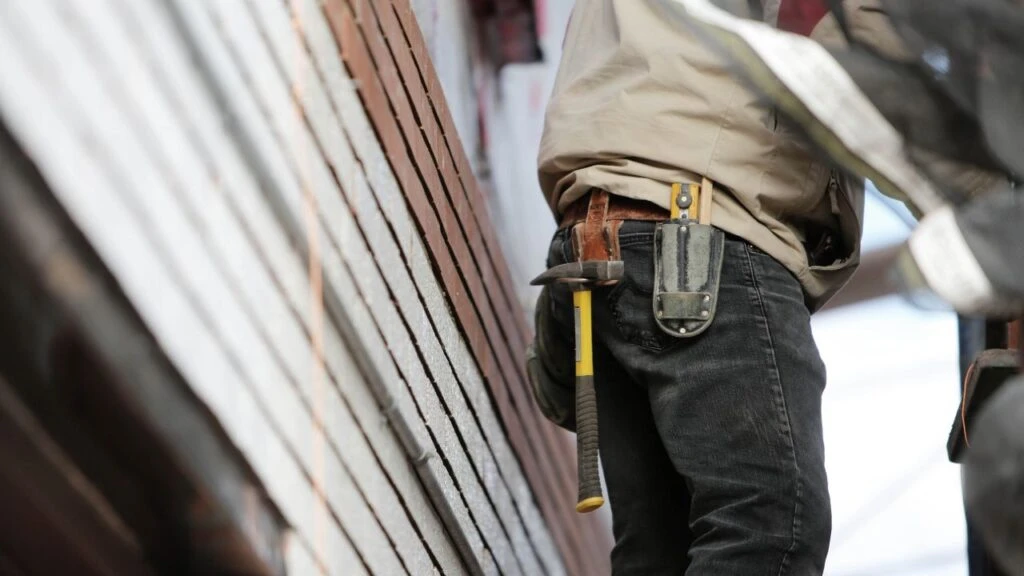 Maintenance professional walking up stairs next to a house