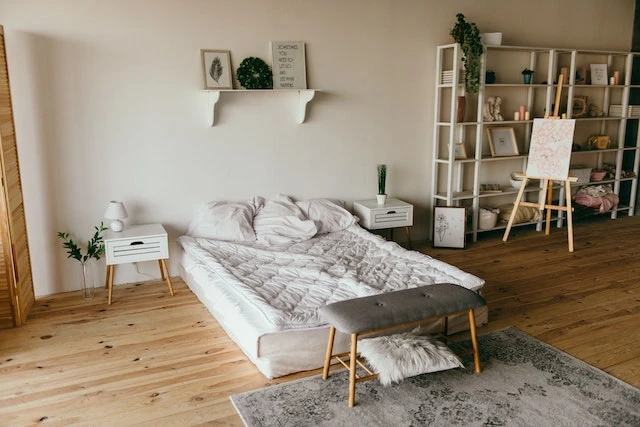 Bedroom interior with a white bed, large bookshelf and hardwood floors