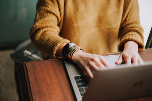 Person in a yellow sweater working on a laptop