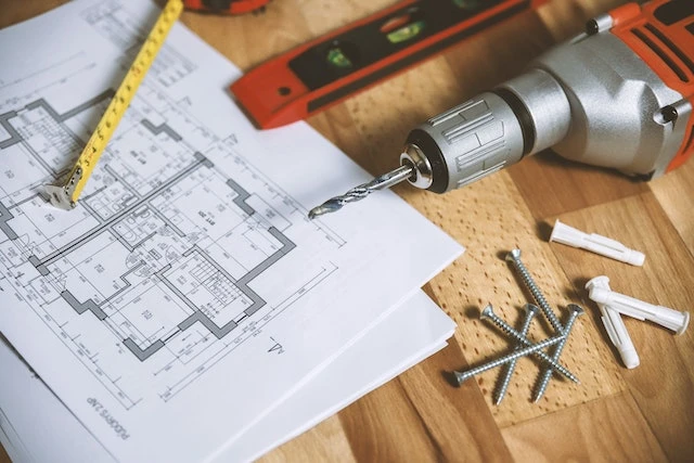 close up of floor plans of a house, drill, screws, tape measure, and level