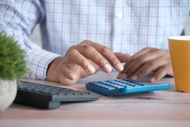 Close up of hands using a blue calculator to calculate fair market rent