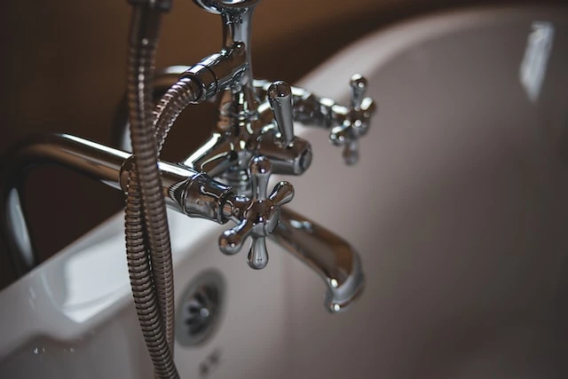 Close up of silver bathtub handles in a white bathtub