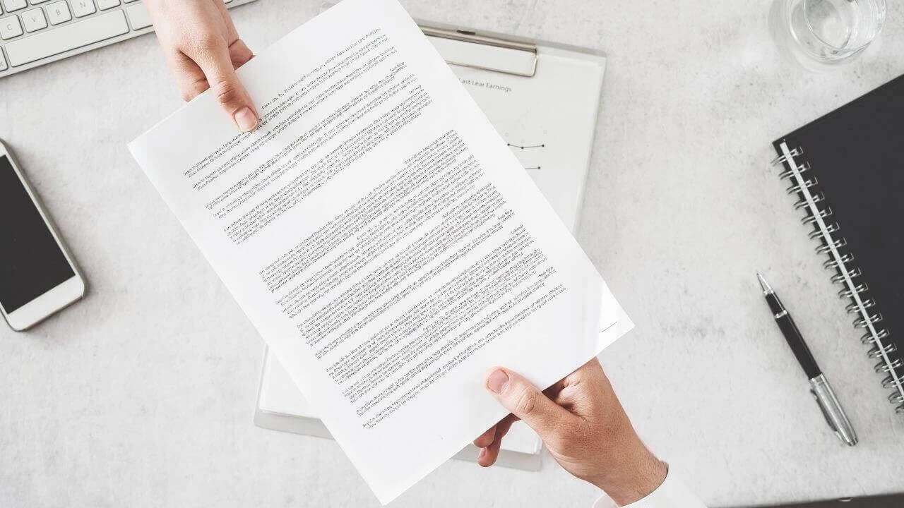 close up of someone handing a lease agreement to another person