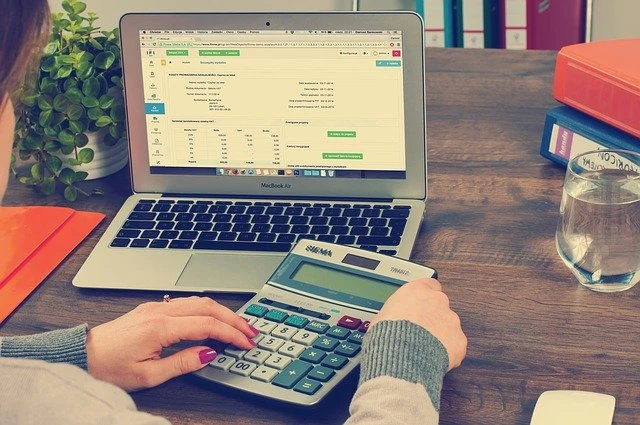 close up of someone using a calculator and a laptop to keep track of online rent payments