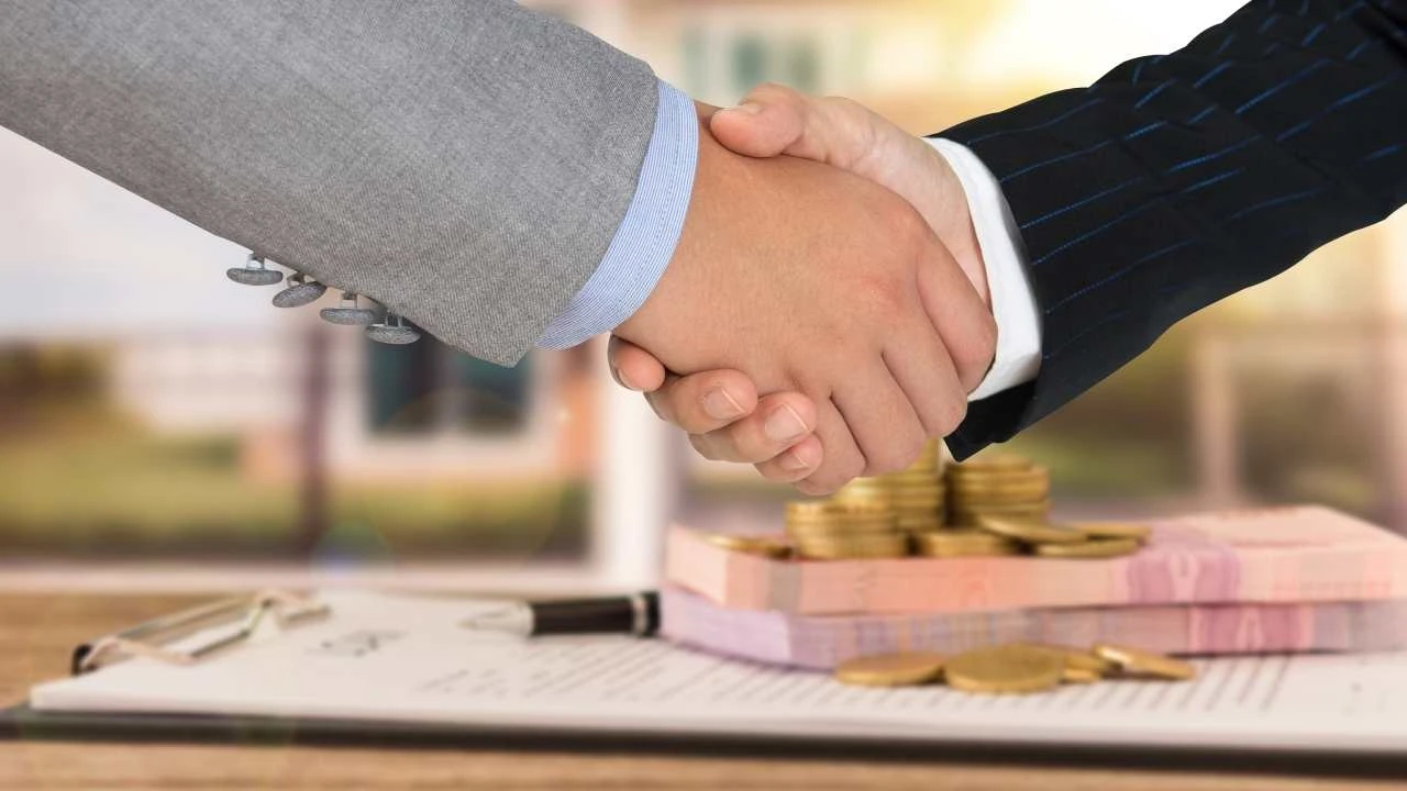 close up of two people in suits shaking hands