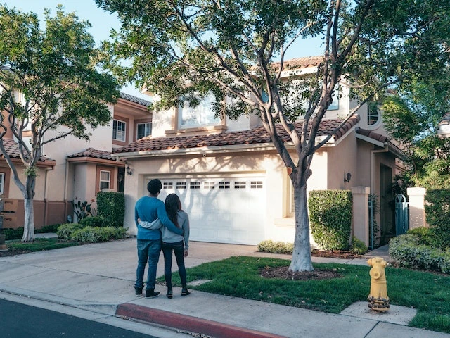 Couple standing in front of a house, happy after completing their tenant screening