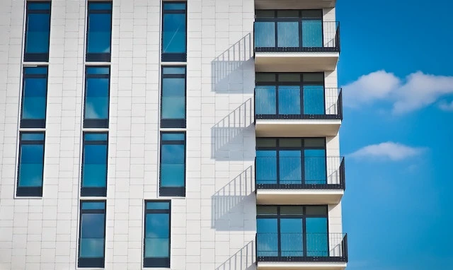 Exterior-of-a-white-apartment-building-with-balconies-in-front-of-a-blue-sky