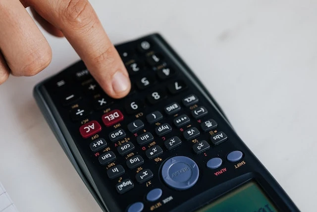 Close-up of a hand pressing a button on a calculator