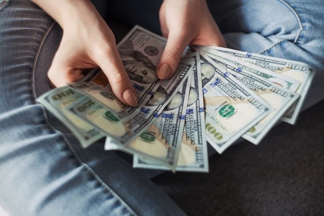 Hands fanning out eight 100 dollar bills