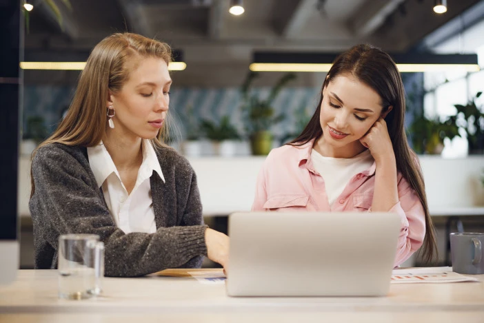 Two colleagues reviewing information together on a laptop in an office