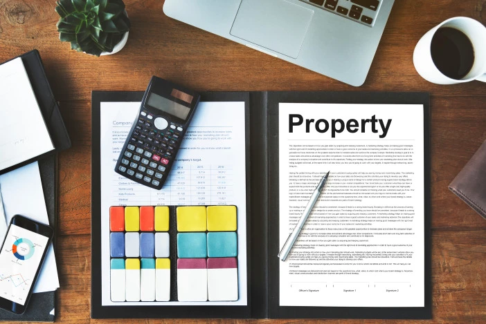 Flat lay of a calculator, budgeting notes, and a property document on a desk