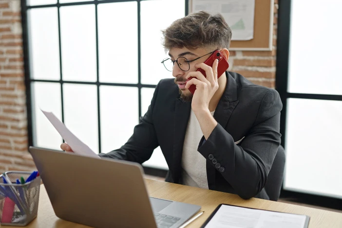 Property manager on the phone at his desk while reviewing paperwork