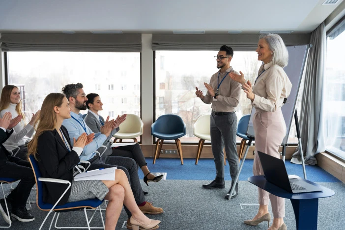 Colleagues applauding a presenter during a networking event in a conference room