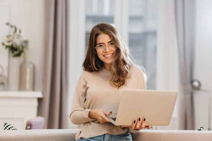 Property manager smiling while holding a laptop in a living room