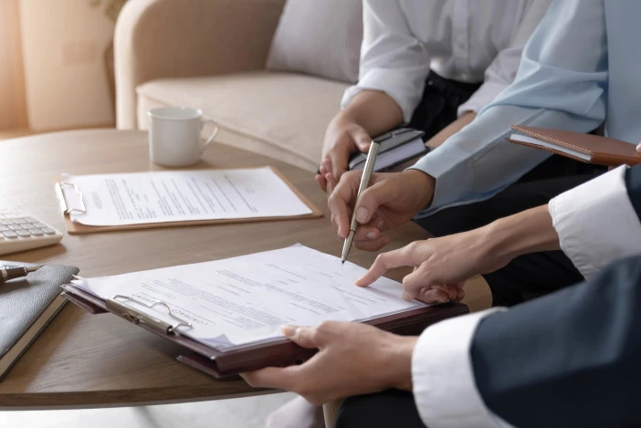 Close up of two people’s hands pointing at a document