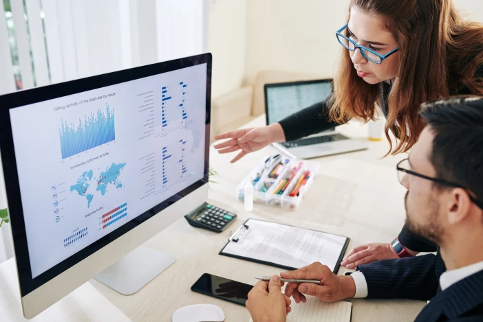 Two property managers looking at data analytics on a desktop computer screen