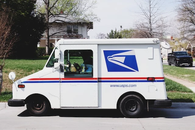 A United State Postal Service truck parked on the side of the road in a residential neighborhood