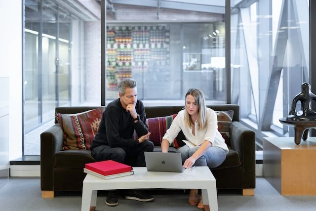 Two people working on a laptop on a couch