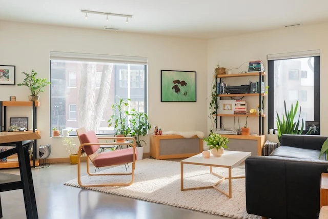 Living room in a modern apartment with grey concrete floors and maple wood furniture