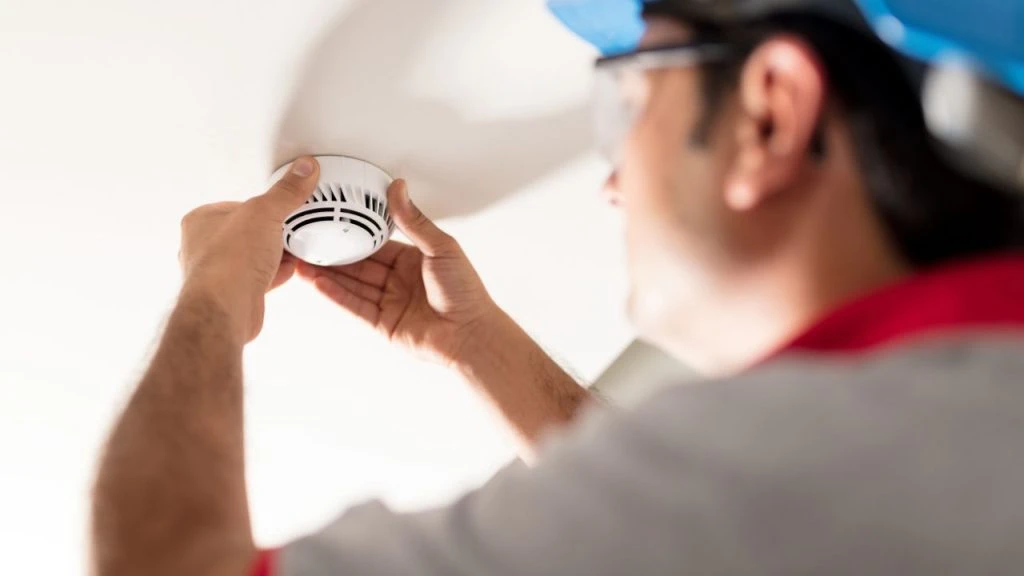 Maintenance worker checking a fire alarm