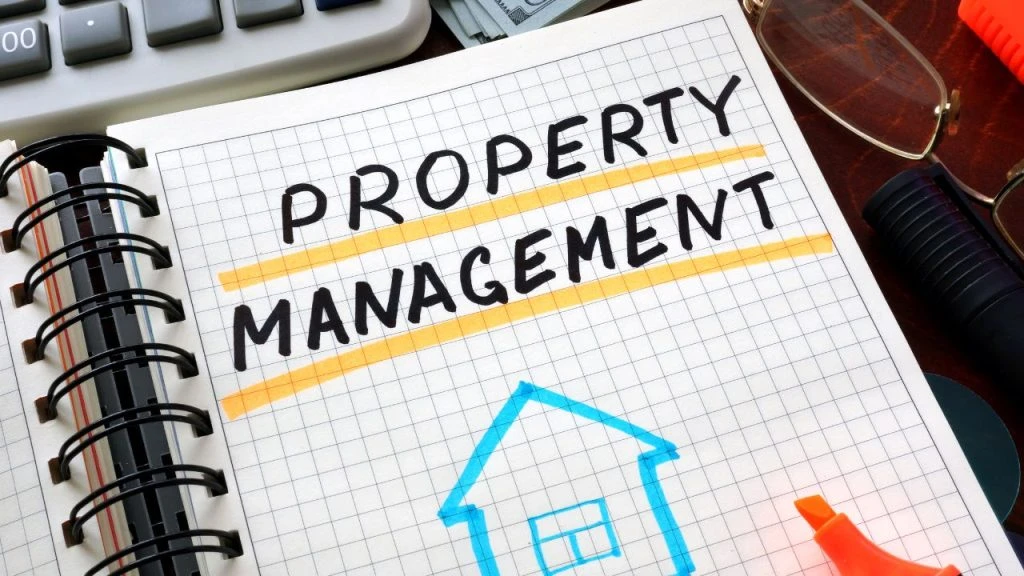 Notebook open to a page that says property management on a messy desk