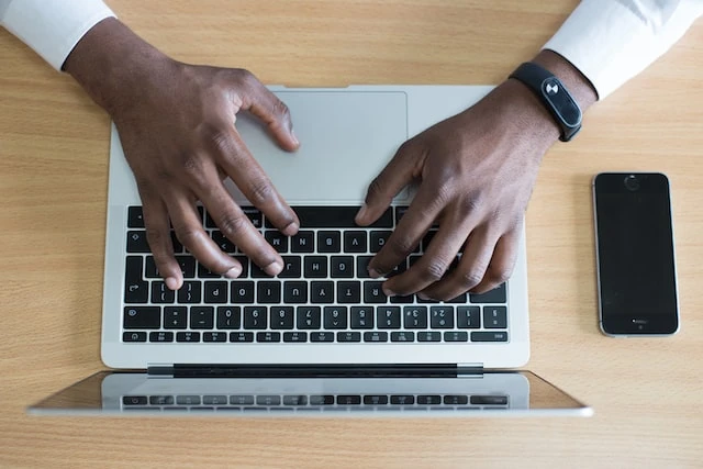 Overhead shot of someone’s hands typing on a laptop