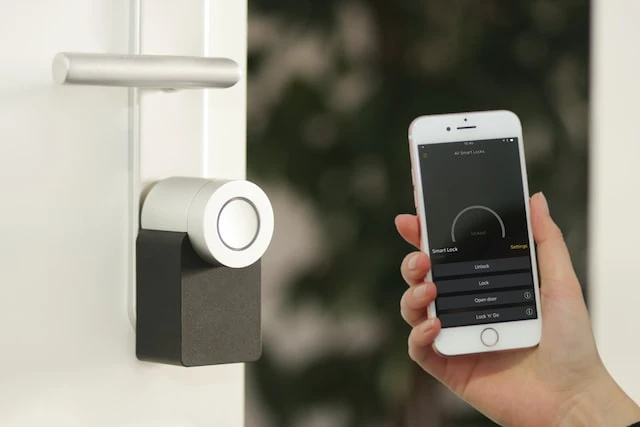 Person holding a smartphone next to a smart doorbell