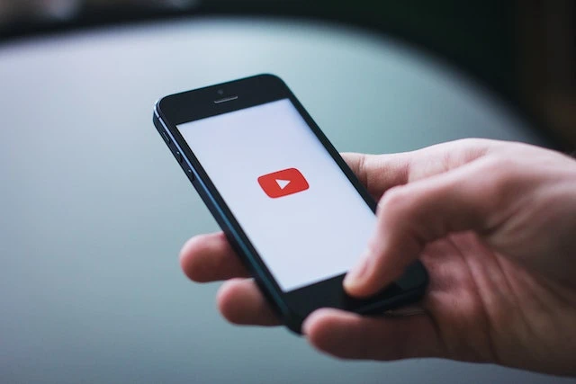 Person Holding Space Gray Iphone 5 with the youtube logo on a white background
