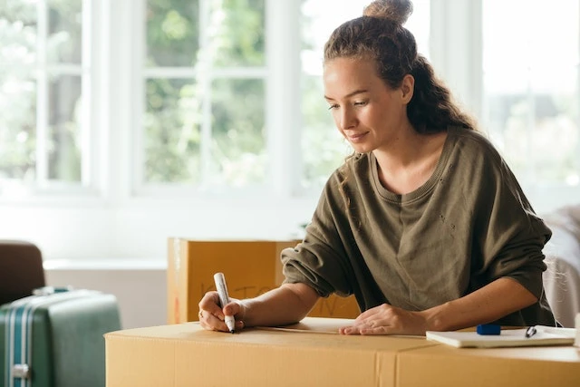 Person sitting and labelling a moving box