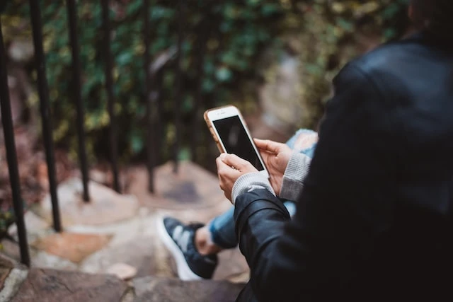 A real estate agent sitting outdoors looking at their phone