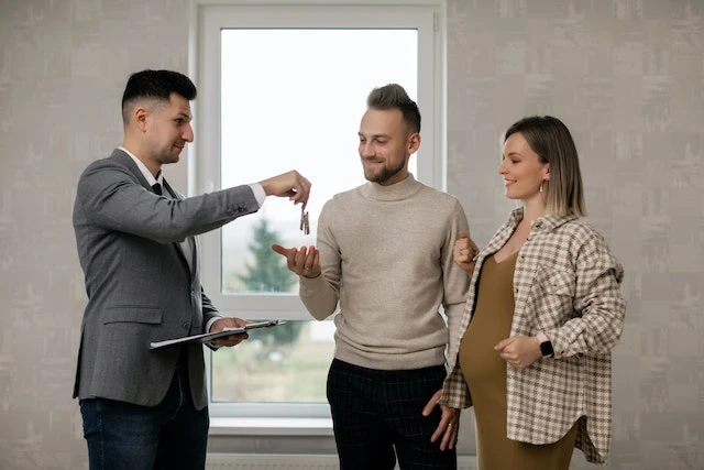 A property manager handing keys to a young couple in their new rental property