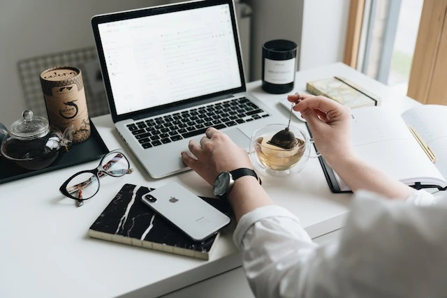 Person using their laptop at a white desk