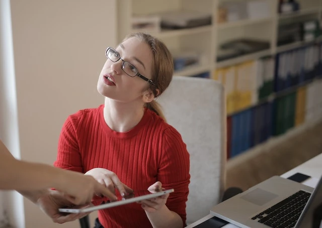 Property management professional wearing glasses pointing at something on a tablet another person is holding