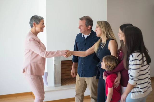 Person in a pink suit shaking hands with a woman who is standing next to her four family members
