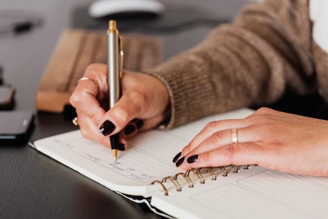 Hands writing in a notebook