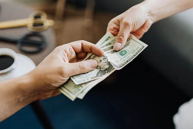 Two hands exchanging dollar bills as money paid for a security deposit