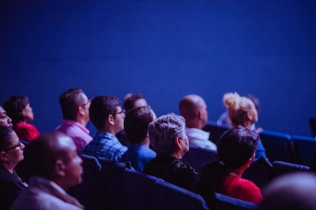 A room with people sitting in chairs looking at a stage