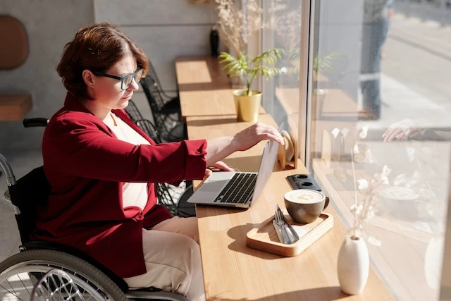 Property manager in a wheelchair working on her laptop in front of a window