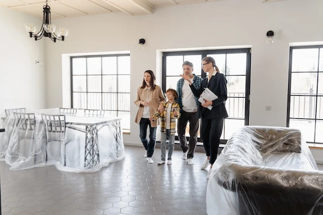 Real estate agent showing a family of three around a new home