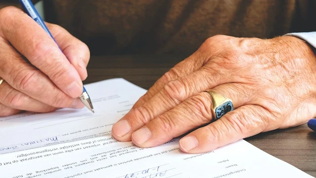 Cropped image of hands holding a fountain pen signing a legal document