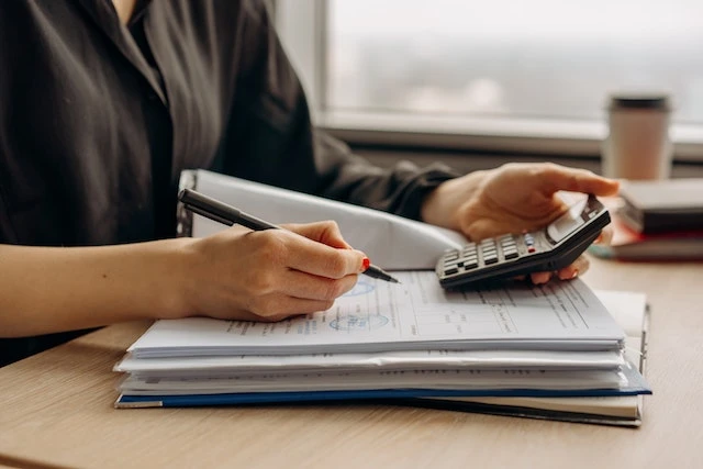 A property management professional using a calculator to work on financial documents