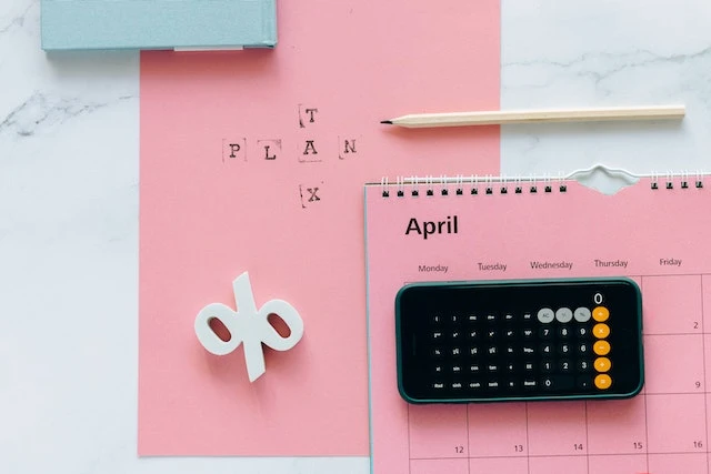 Pink calendar and phone open to a calculator on a pink background that says TAX PLAN